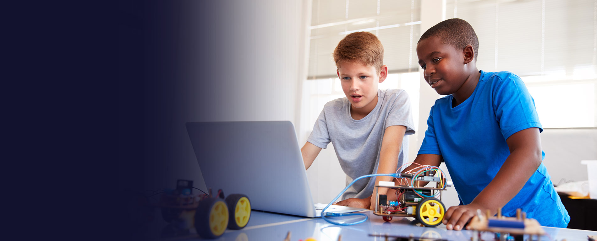 Two elementary-school-age boys working on a robotics project together