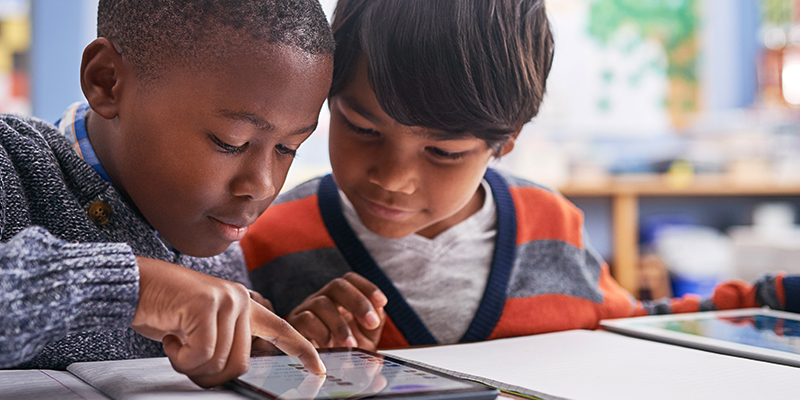 Two young children using an electronic tablet together