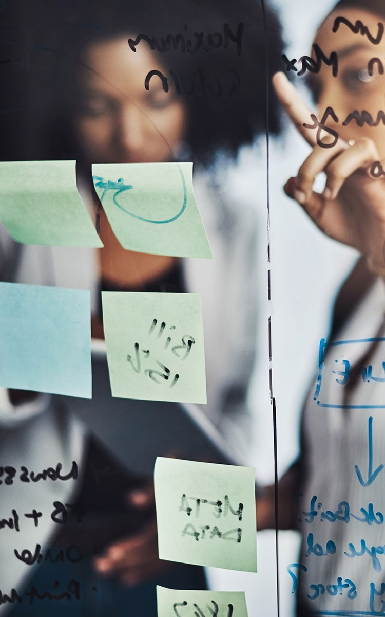 Two women discuss items on a whiteboard