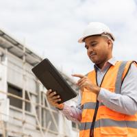 Worker in safety vest and hard hat on tablet