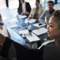 Woman writing on board with co-workers looking