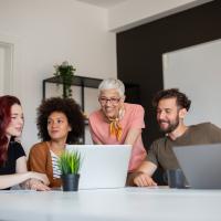 Three women and two men in front of laptops in office
