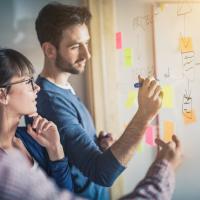 Man and woman planning at white board