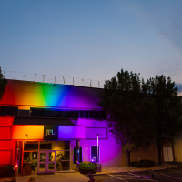 Photo of the JPL building at night, illuminated by rainbow lights