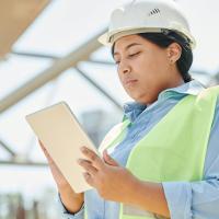 Woman in safety vest reviewing document on clipboard