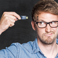 Man with glasses looking at a thumb drive held in his hand