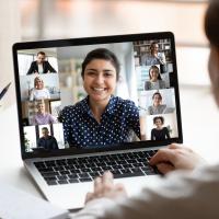 photo of a male worker having a virtual meeting with multiple workers on a laptop