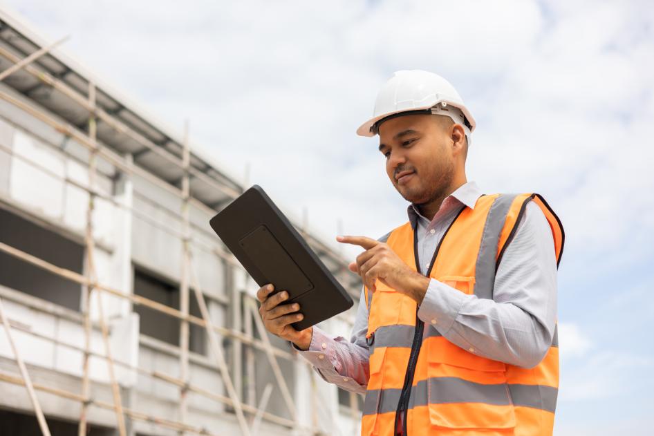 Worker in safety vest and hard hat on tablet