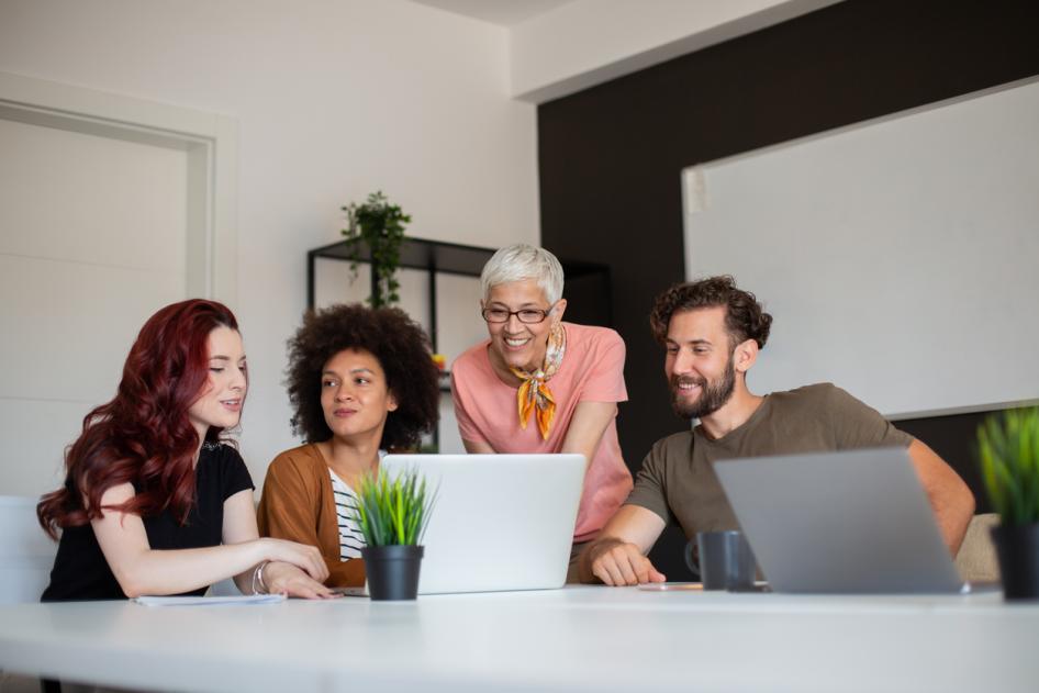 Three women and two men in front of laptops in office