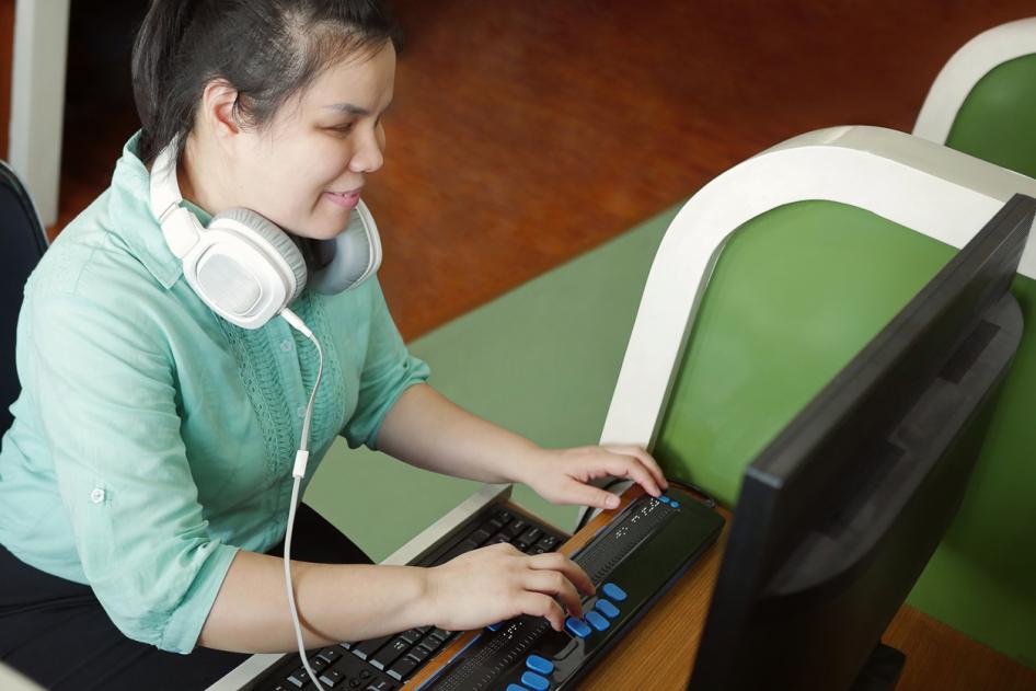 Young Asian blind woman at computer