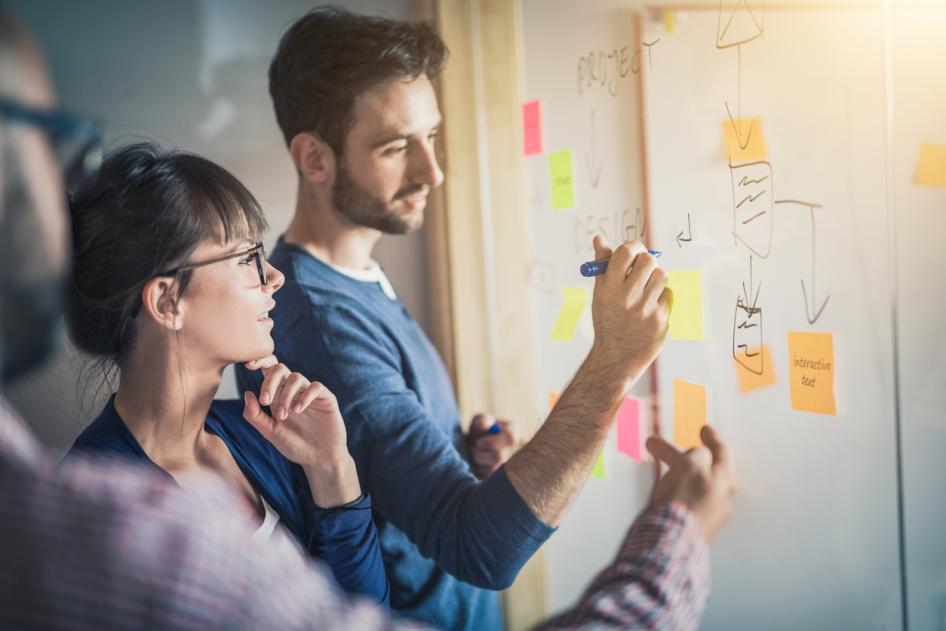 Man and woman planning at white board