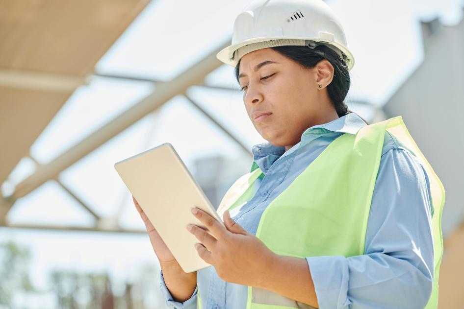 Woman in safety vest reviewing document on clipboard