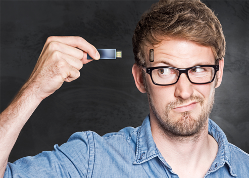 Man with glasses looking at a thumb drive held in his hand