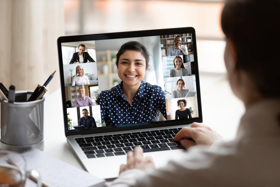 photo of a male worker having a virtual meeting with multiple workers on a laptop